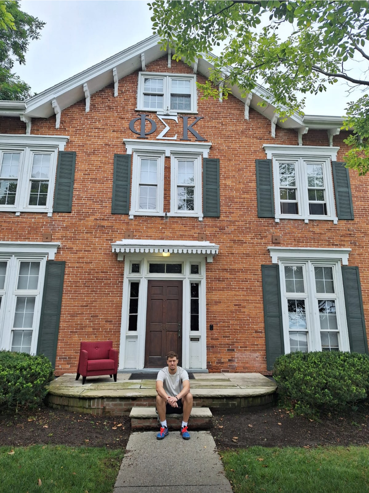 Vicente Lyon sitting outside of the Psi Triton house at Hobart College 
